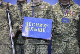 Participant of the congress holds a poster with the words "Honest More"