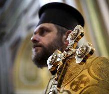 The clergyman holds the cross