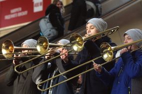 Participants of the Great Choral Fleshmobile play on trumpets