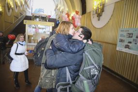 Молодые мужчина и женщина целуются в помещении станции фуникулера