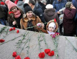 The girl puts flowers to the monument