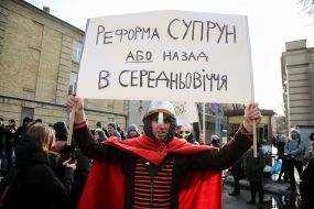 A participant of the action in support of Ulyana Suprun in a knight's suit holds a poster