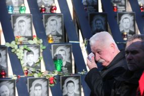 A man wipes tears near the photos of the Heroes of Heavenly Hundred