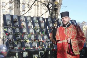 A priest with a censer near the photos of the Heroes of Heavenly Hundreds
