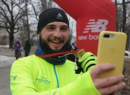 Участник пробега "Snow Run" делает селфи с медалью