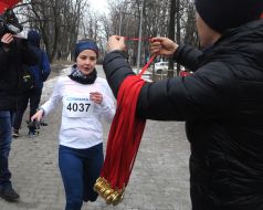 Мужчина встречает с медалью участницу пробега "Snow Run"