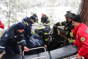 Rescuers try to unlock people from an inverted car