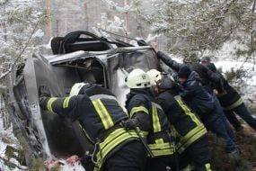 Rescuers try to unlock people from an inverted car