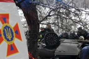 Rescuers try to unlock people from an inverted car