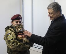Petro Poroshenko strokes a cat in the hands of a female soldier