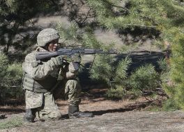 Military with weapons covers the evacuation of a wounded soldier