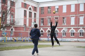 Лицеисты играют в волейбол на спортивной площадке