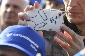 The participant of the action holds the phone with a cover in the form of a cat