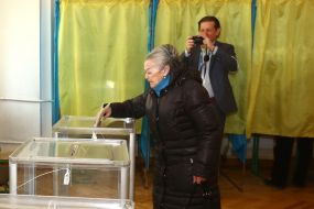 Жінка вкидає бюлетень в урну для голосування 