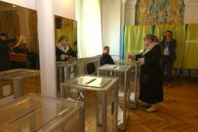 Жінка вкидає бюлетень в урну для голосування 