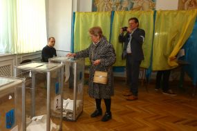 Жінка вкидає бюлетень в урну для голосування 