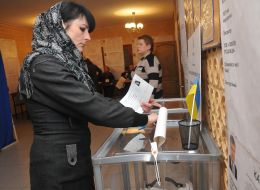 Жінка вкидає бюлетень в урну для голосування