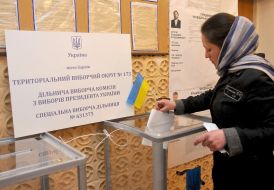 Жінка вкидає бюлетень в урну для голосування