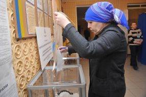 Жінка вкидає бюлетень в урну для голосування