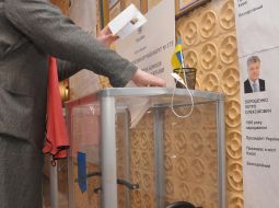 Жінка вкидає бюлетень в урну для голосування