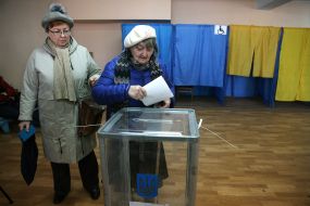 A woman puts a ballot in a ballot box