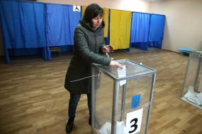 A woman puts a ballot in a ballot box
