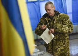 A serviceman puts a ballot in a ballot box