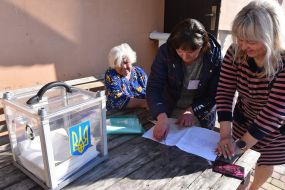 Члены избирательной комиссии выдают бюллетень пожилой женщине