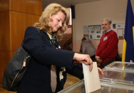 A woman throws a ballot in a ballot box
