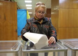 A woman throws a ballot in a ballot box
