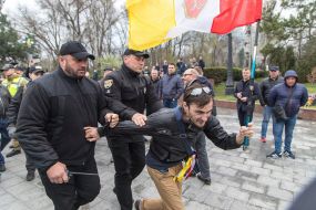 Police detain a man with St. George ribbon