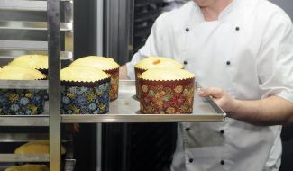 Повар держит противень с куличами