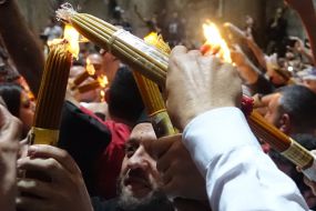 Believers hold candles lit from the Blessed Fire
