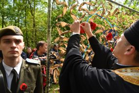 The priest places the poppy on the map of Ukraine