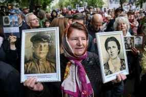 Participant of action "Immortal Regiment" holds photos