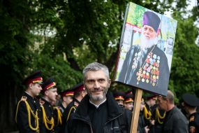 Участник акции "Бессмертный полк" держит портрет священнослужителя