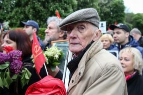 Participant of the action "Immortal Regiment" holds a flag with symbols of the CPU