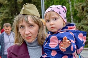 Женщина в пилотке держит девочку на руках