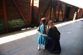 A woman with a girl in the Crimean Tatar costumes near a trolley car