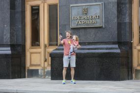 Мужчина с дочкой делают селфи возле здания АПУ