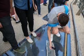 Мужчина фотографирует через стеклянную поверхность моста