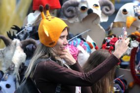 A girl tries a hat in the form of a giraffe's head