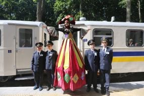 Boys in the form of railway workers and a girl on stilts