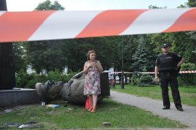 A woman stands near the tumbled bust of George Zhukov