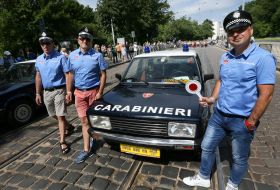 Men in a stylized form of carabiners near a retro car