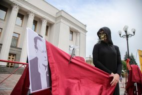 Participant in the performance in the costume of death near portraits of people's deputies