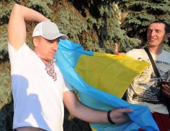 The participant of the protest action covers the shoulders of the Ukrainian flag