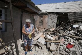 A woman collects things near the ruined house in Marinka