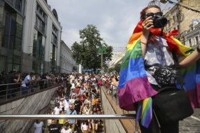 The participant of the "March of Equality" with the flag of LGBT on the shoulders is taking pictures