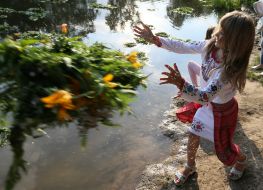 Girls in embroidery wreaths of wild flowers in the water